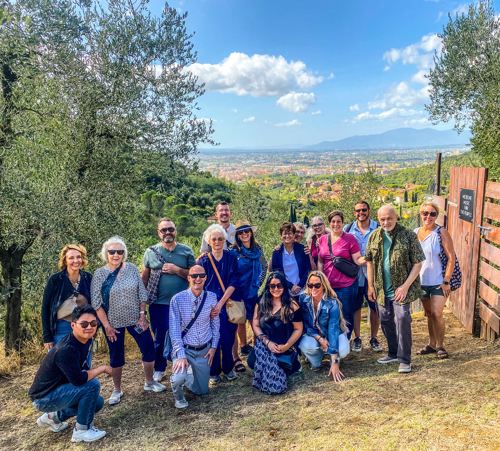 a group of travelers posing for a photo in an olive grove in front of the town of Montecatini 