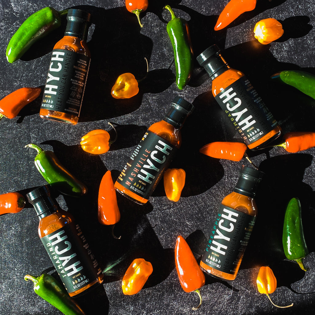 bottles of HYCH hot sauce with chili peppers