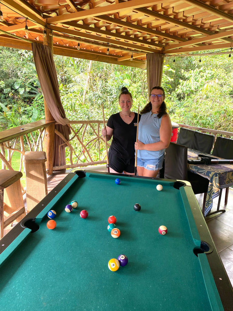 Two women playing pool on the covered deck at Finca Mia