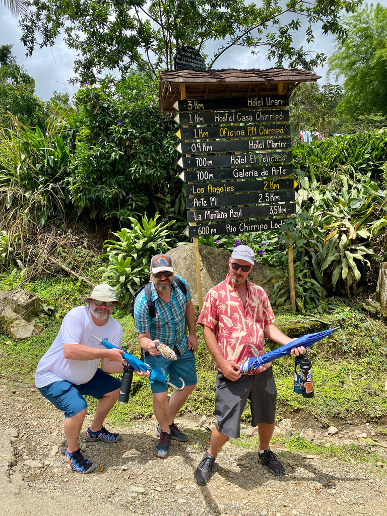 Three men with umbrellas on a hike in Costa Rica